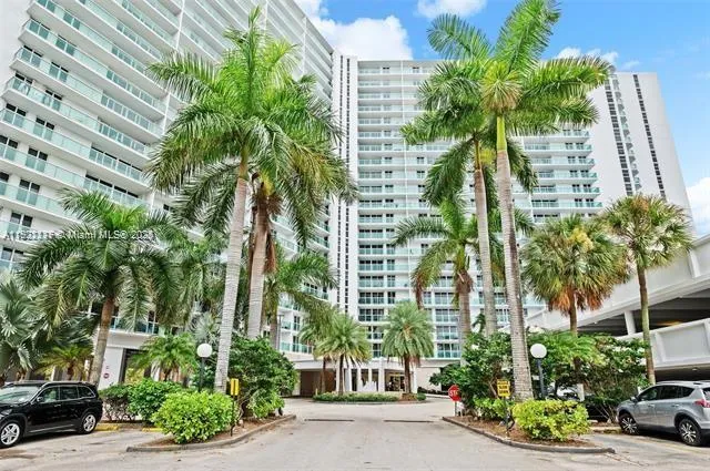 front view of a multi story building with a yard and potted plants