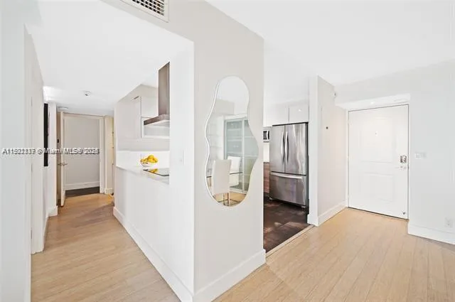 a view of a kitchen with a refrigerator a stove top oven and hallway