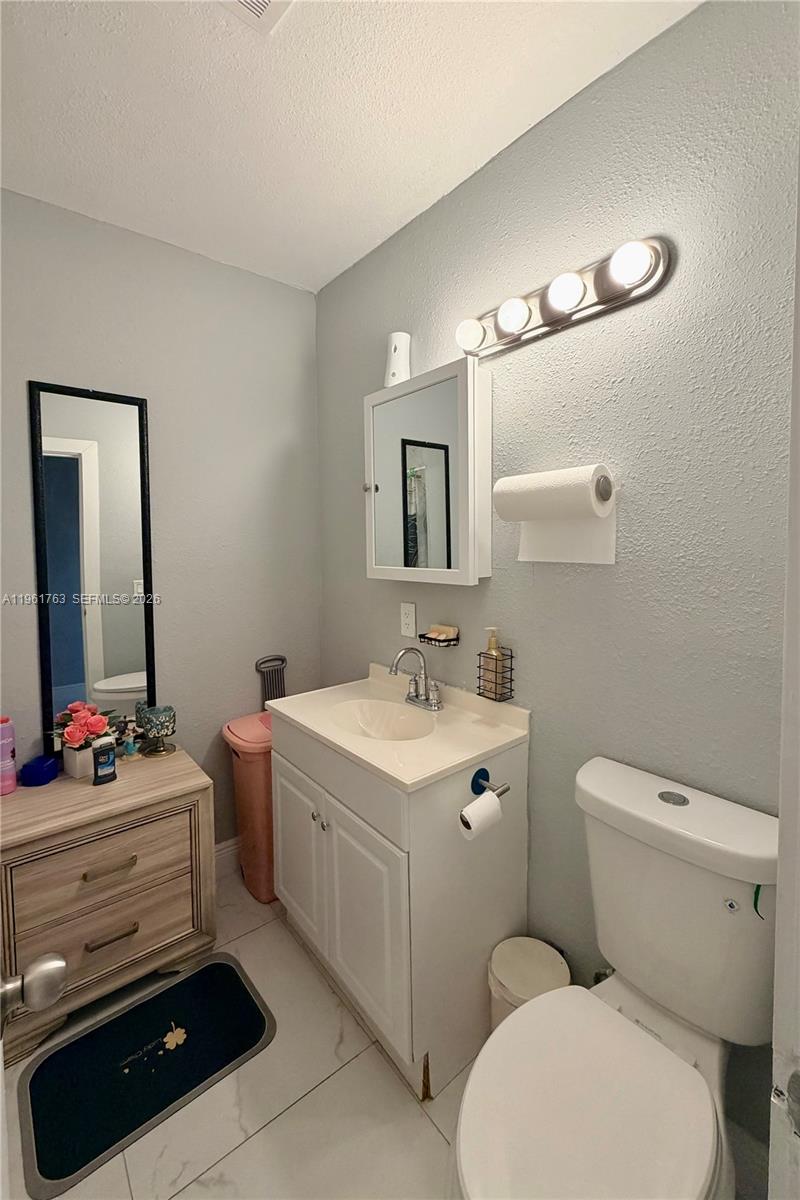 598 East 41st Street Hialeah, FL 33013 - Photo 9 of 15 a bathroom with a toilet a sink and mirror