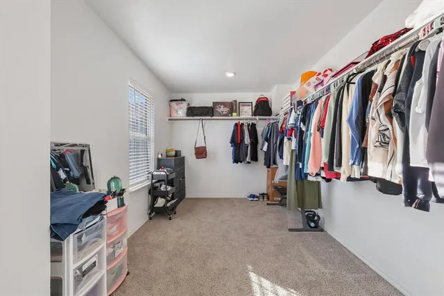 a view of walk in closet with clothes and shoes