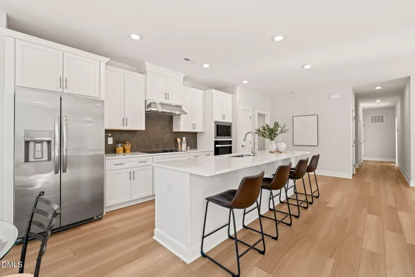 a kitchen with stainless steel appliances a refrigerator a stove top oven and a center island with wooden floor