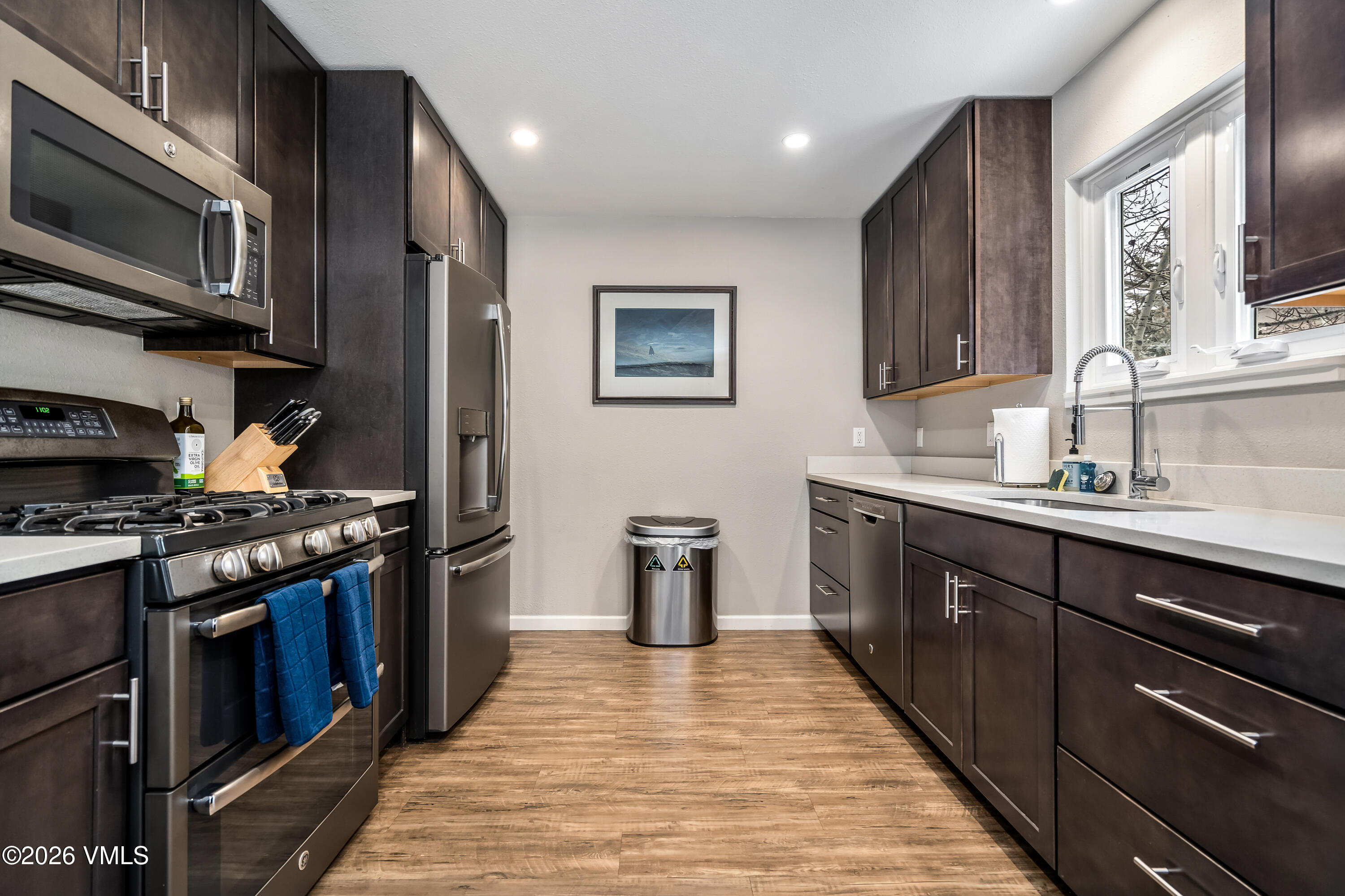 212 Eagle Road Eagle-Vail, CO 81620 - Photo 9 of 25 a kitchen with stainless steel appliances granite countertop a refrigerator a stove top oven a sink dishwasher and wooden cabinets with wooden floor