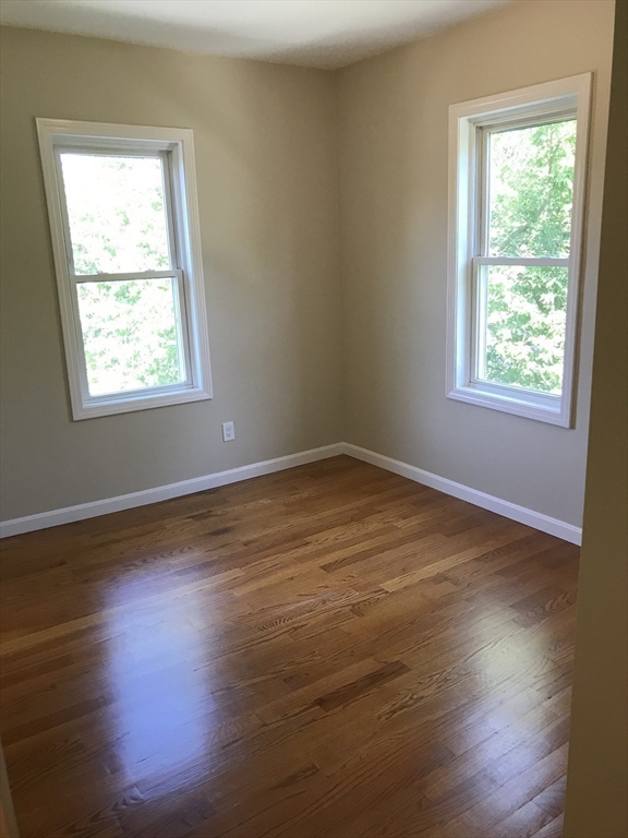73 Broadway, Unit 3 Quincy, MA 02169 - Photo 11 of 16 an empty room with wooden floor and windows