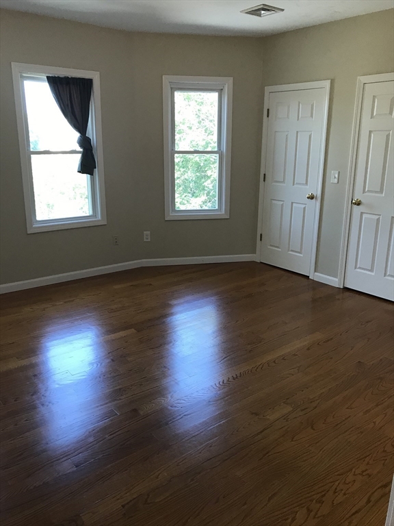 73 Broadway, Unit 3 Quincy, MA 02169 - Photo 16 of 16 an empty room with wooden floor and windows