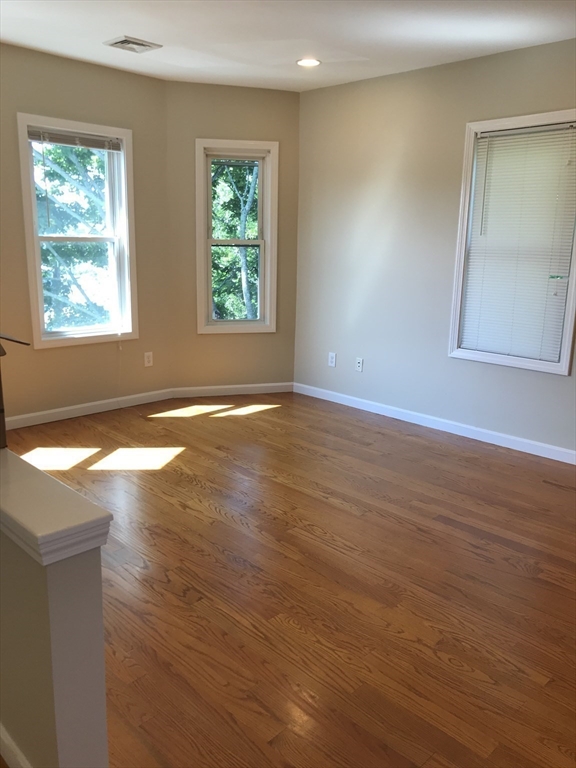 73 Broadway, Unit 3 Quincy, MA 02169 - Photo 5 of 16 an empty room with wooden floor and windows