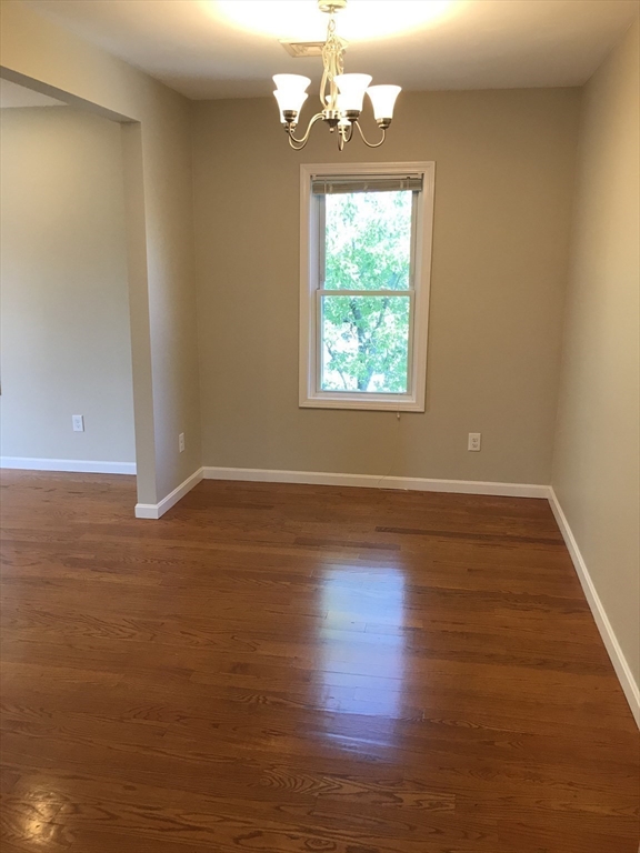 73 Broadway, Unit 3 Quincy, MA 02169 - Photo 6 of 16 an empty room with wooden floor and windows