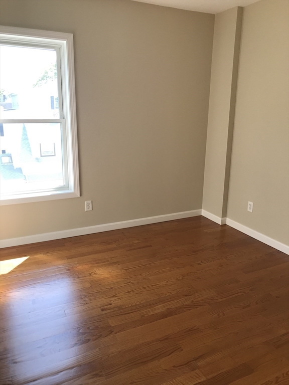 73 Broadway, Unit 3 Quincy, MA 02169 - Photo 10 of 16 an empty room with wooden floor and windows