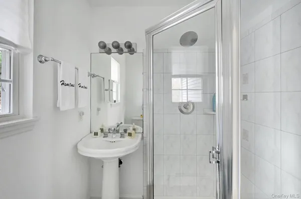 a bathroom with a sink a mirror a window and glass door
