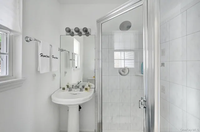 a bathroom with a sink a mirror a window and glass door