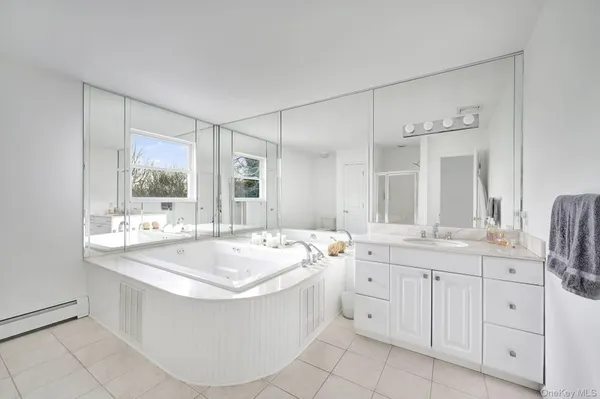 a large white bathroom with a double vanity sink a mirror and a bathtub