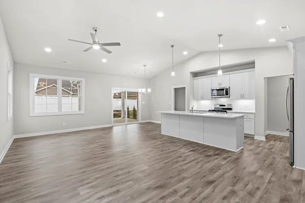 a large kitchen with stainless steel appliances a large counter top a sink a refrigerator and a window