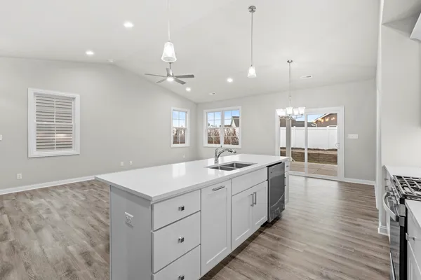 a large kitchen with kitchen island a stove a sink a center island and wooden floor
