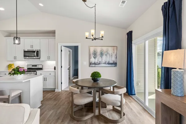 a kitchen with stainless steel appliances a dining table chairs a refrigerator and a window