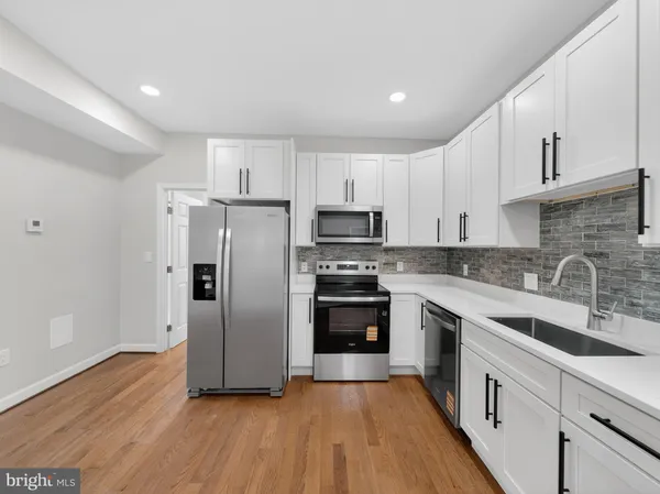 a kitchen with stainless steel appliances granite countertop a refrigerator a sink dishwasher a stove oven and white countertops with wooden floor