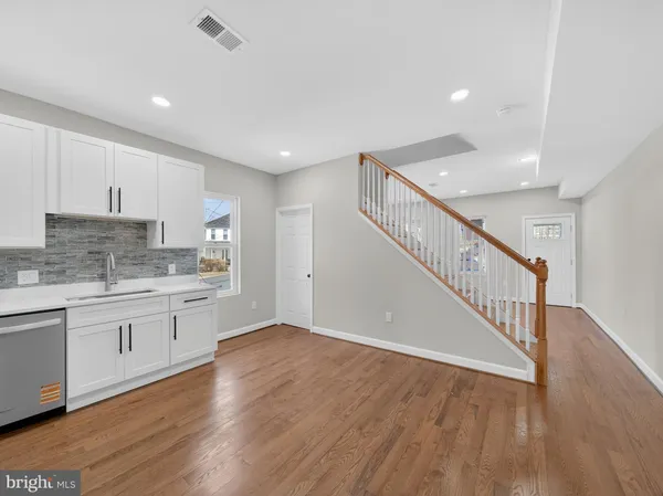 a open hall with cabinets wooden floor and a sink