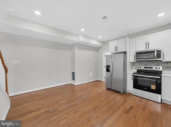 a view of a kitchen with a refrigerator a stove top oven cabinets