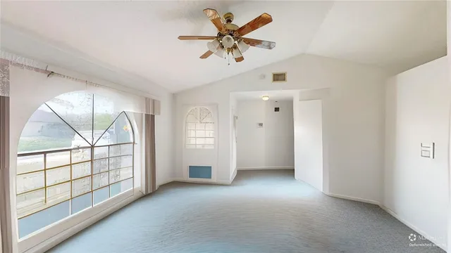 an empty room with chandelier fan and windows