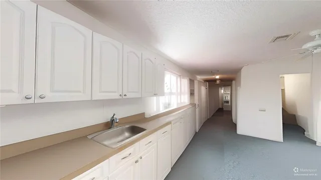 a kitchen with granite countertop a sink and white cabinets