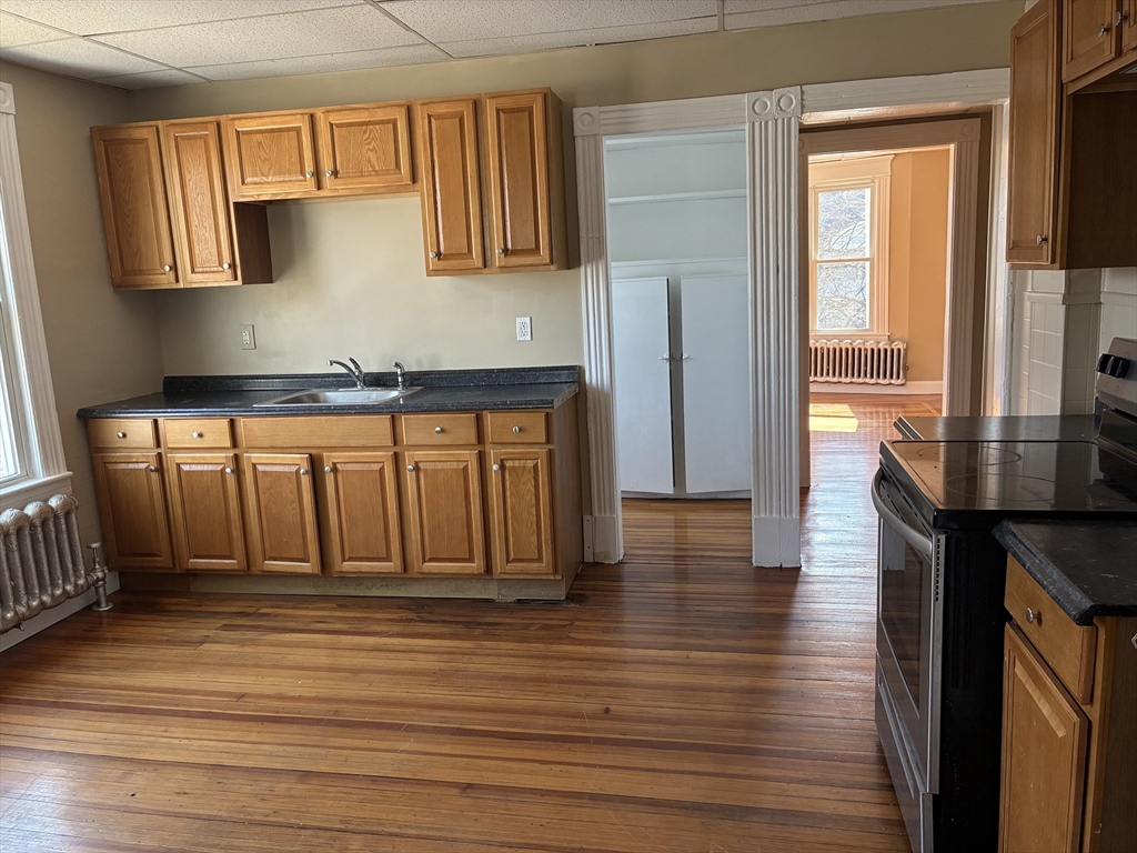 658 Sumner Avenue, Unit 2 Springfield, MA 01108 - Photo 5 of 11 a kitchen with stainless steel appliances wooden floor and a window