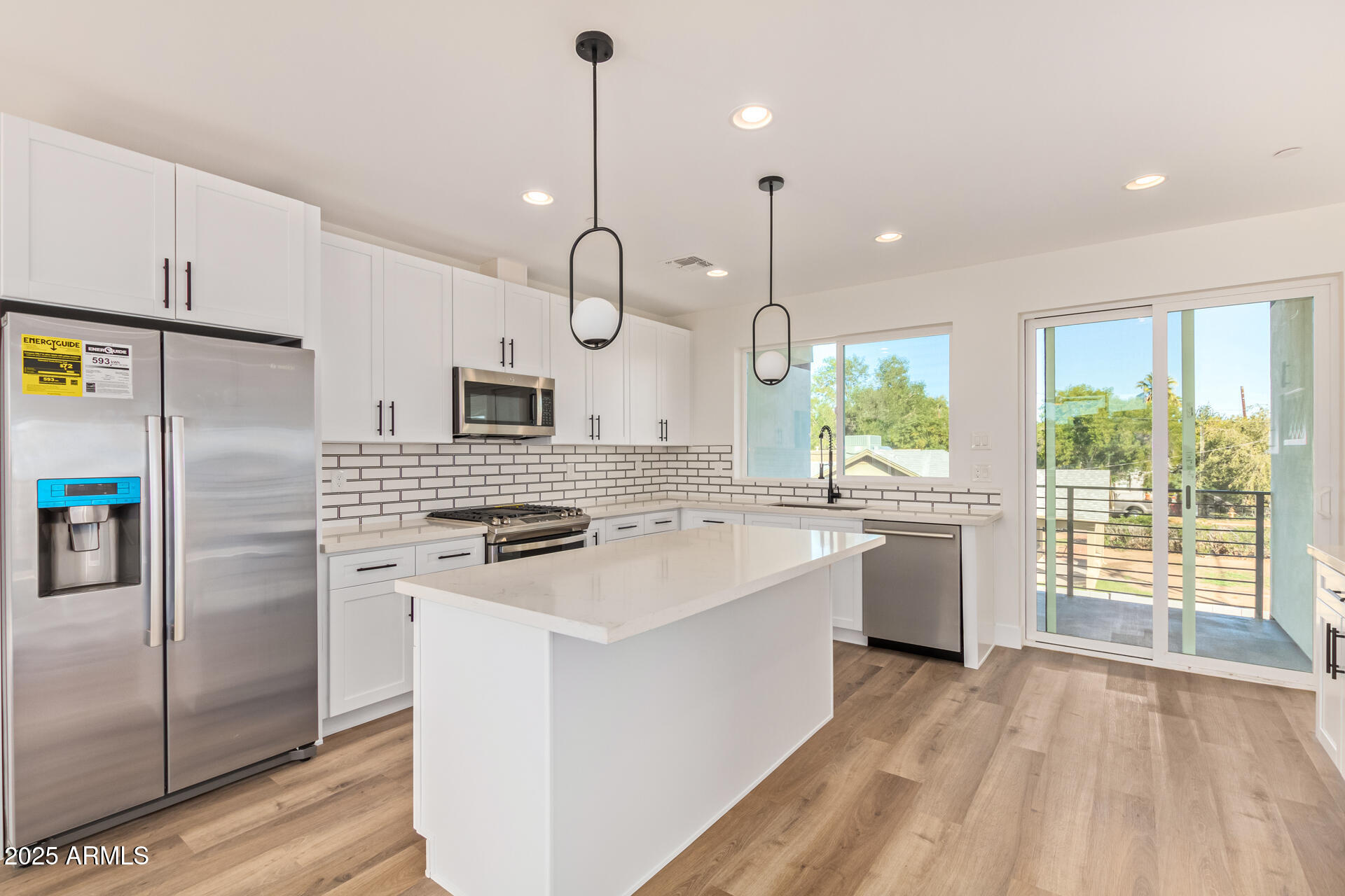 3616 North 12th Street Phoenix, AZ 85014 - Photo 14 of 25 a kitchen with stainless steel appliances granite countertop a sink a stove a refrigerator a island with wooden floor and cabinets