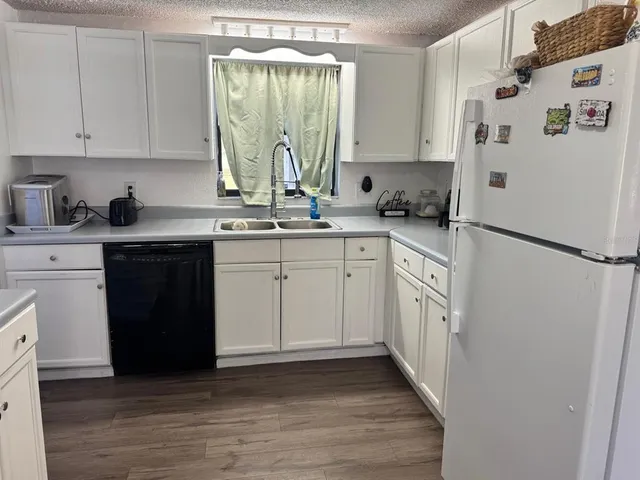a kitchen with stainless steel appliances granite countertop a refrigerator sink and white cabinets