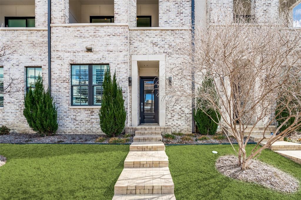5421 Patterson Street Irving, TX 75039 - Photo 9 of 32 White brick facade featuring a dark entry door with transom window, stone-finished steps, and black-framed windows