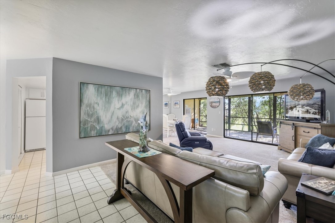 4728 Orange Grove Boulevard, Unit 8 North Fort Myers, FL 33903 - Photo 3 of 31 a living room with furniture a large window and a chandelier