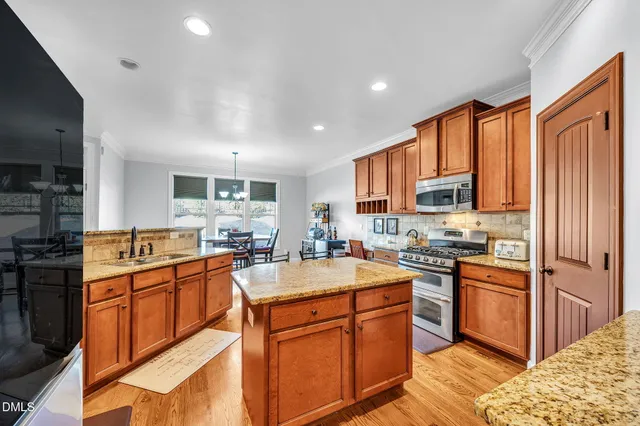 a kitchen with stainless steel appliances granite countertop a stove top oven a sink dishwasher a refrigerator and cabinets with wooden floor