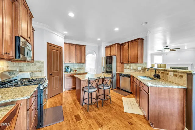 a kitchen with granite countertop kitchen island stainless steel appliances a stove a sink a refrigerator cabinets and dining table