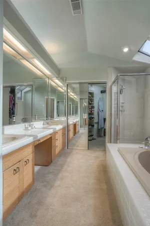 a large bathroom with a granite countertop double vanity sink a large mirror a bathtub and shower
