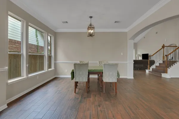 a dining room with wooden floor a chandelier a glass table and windows