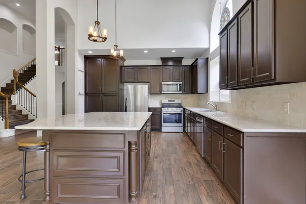 a kitchen with stainless steel appliances a dining table chairs refrigerator and cabinets