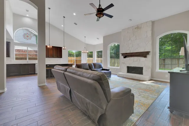 a living room with furniture a fireplace a flat screen tv and a large window