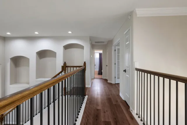a view of a hallway with wooden floor and windows