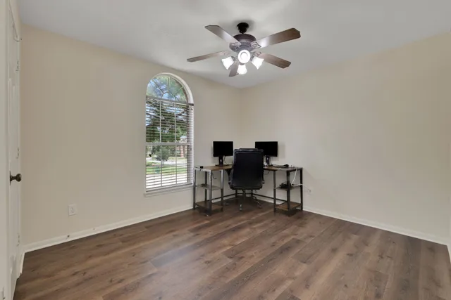 a view of a workspace with wooden floor and a window