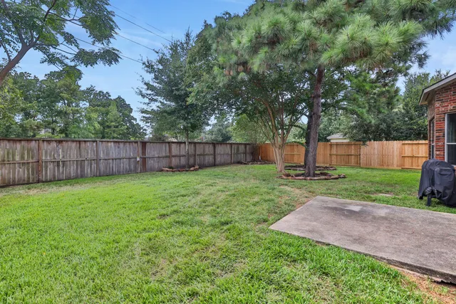 a view of a backyard with large trees and wooden fence