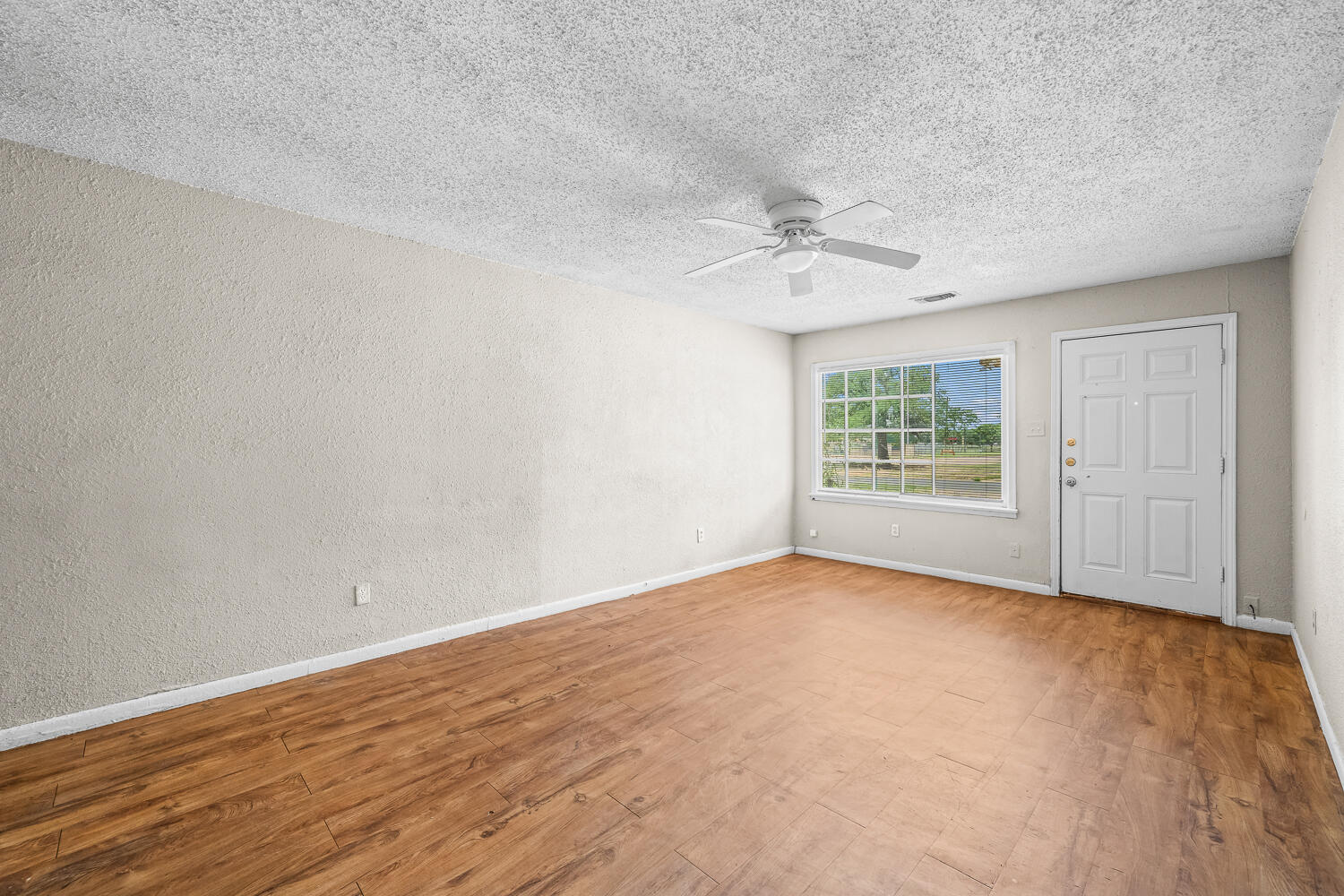1603 27th Street, Unit A Lubbock, TX 79411 - Photo 3 of 13 wooden floor in an empty room with a window