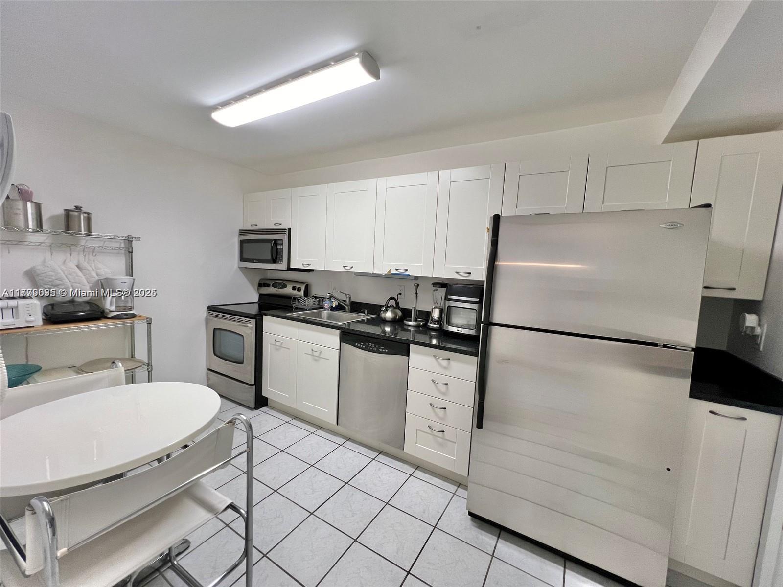 9273 Collins Avenue, Unit 801 Surfside, FL 33154 - Photo 7 of 15 a kitchen with a refrigerator a stove and white cabinets