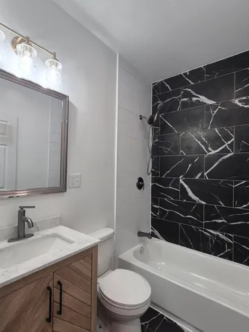 a bathroom with a sink a toilet a mirror and shower