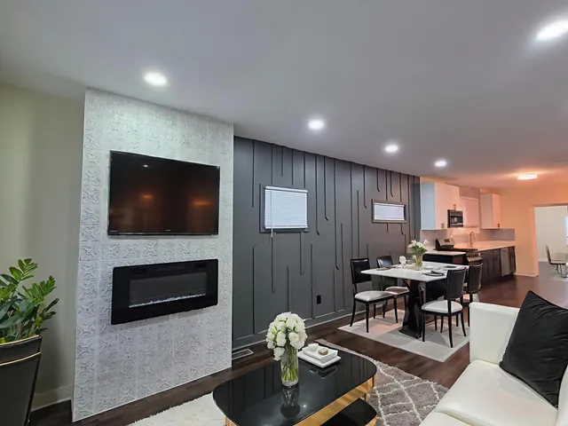 a living room with furniture a flat screen tv and kitchen view