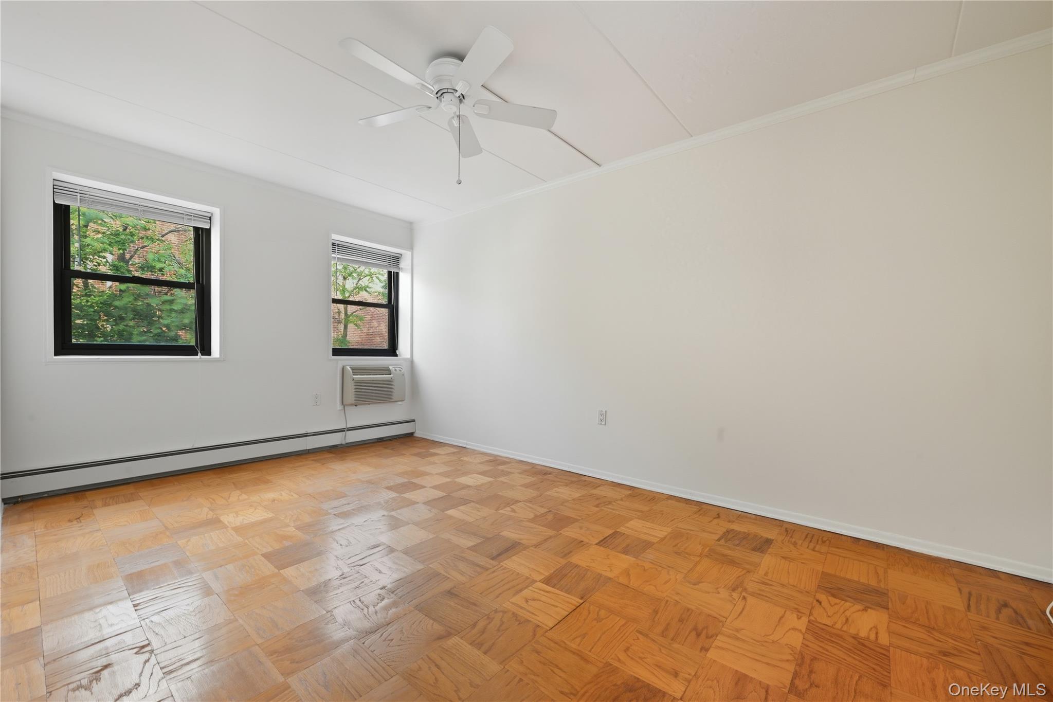 100 Clinton Avenue, Unit 2J Mineola, NY 11501 - Photo 11 of 24 an empty room with windows and ceiling fan