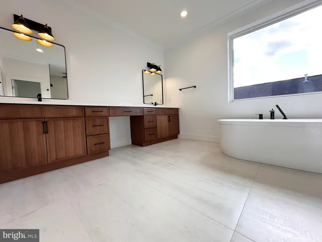 a spacious bathroom with a tub sink and mirror