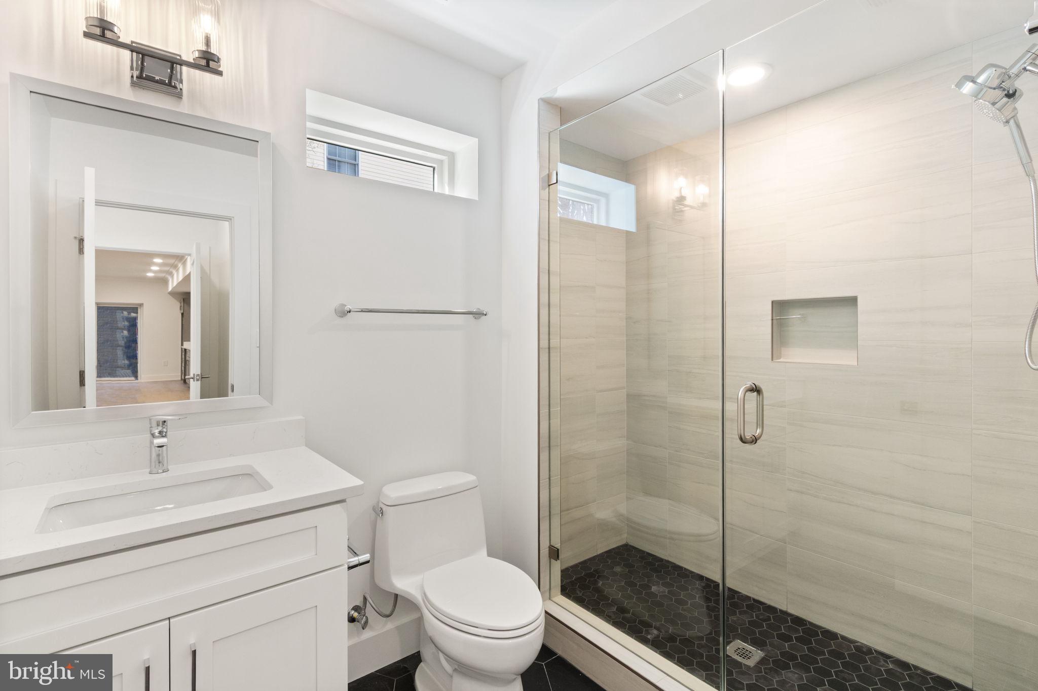 4017 Woodland Road Annandale, VA 22003 - Photo 72 of 76 a bathroom with a sink a toilet a glass door and shower