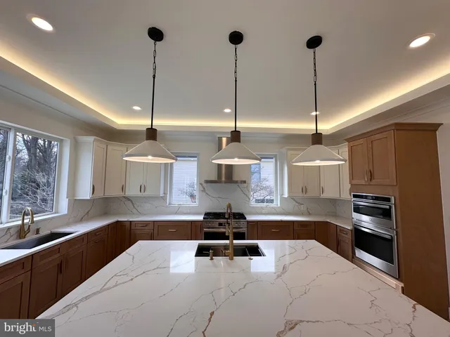 a kitchen with stainless steel appliances kitchen island granite countertop a sink a stove and a wooden floors