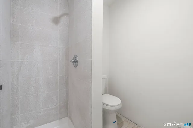 a white toilet sitting next to a shower