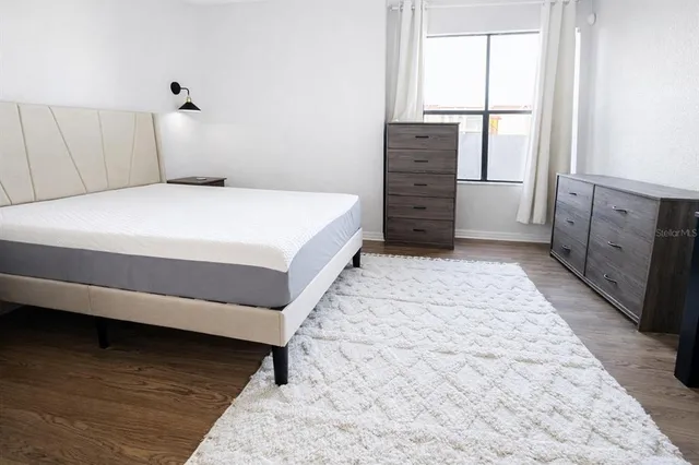 a bed sitting in a bedroom next to a window and wooden floor