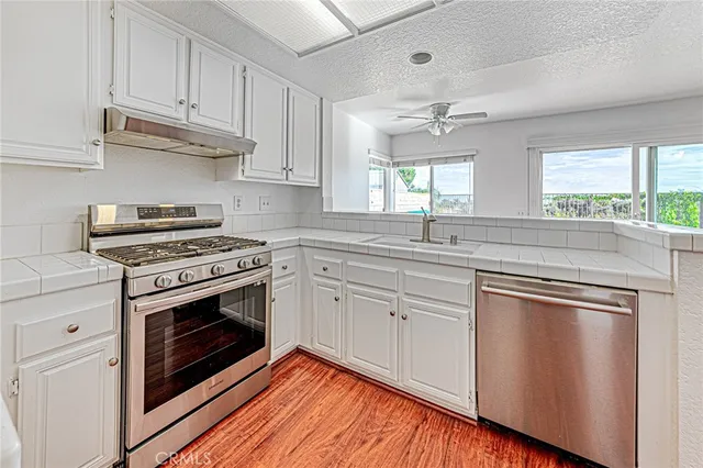 a kitchen with cabinets stainless steel appliances a sink and window