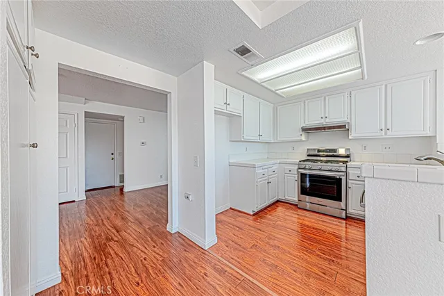 a kitchen with granite countertop wooden floors and white stainless steel appliances