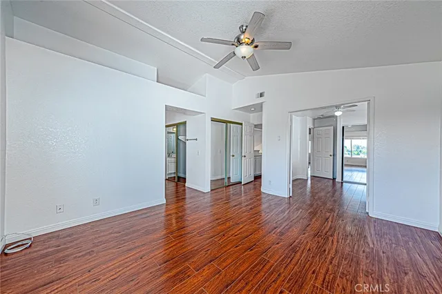 a view of empty room with wooden floor and ceiling fan