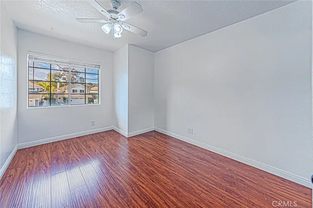 a view of an empty room with window and wooden floor